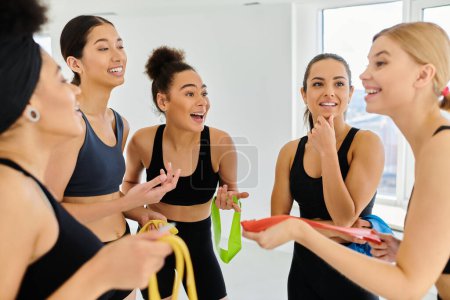 Photo for Group of happy diverse sportswomen holding resistance bands and talking after pilates workout - Royalty Free Image