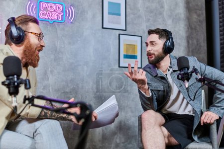 intervieweur attrayant avec les cheveux roux et son invité avec écouteurs discuter des questions, podcast