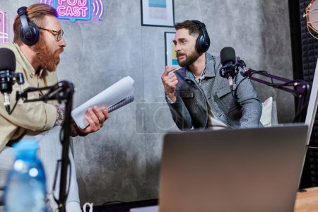 gut aussehende, stylische Männer mit Bart und Kopfhörer, die während eines Podcasts im Studio Fragen diskutieren