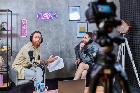Photo for Good looking stylish interviewer talking to his young guest with headphones during podcast - Royalty Free Image