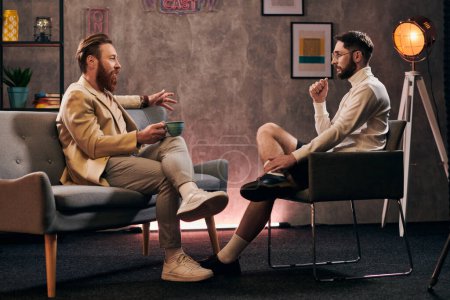 Engagierte Männer mit Bärten in eleganten Anzügen sitzen beim Interview und diskutieren Fragen