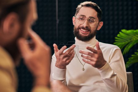 Photo for Cheerful bearded man with glasses in elegant outfit sitting and looking at his interviewer - Royalty Free Image