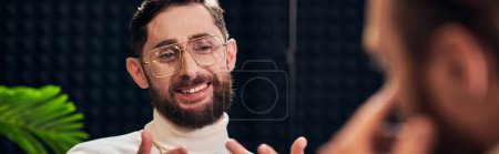 Photo for Cheerful bearded man with glasses in elegant outfit sitting and looking at his interviewer, banner - Royalty Free Image