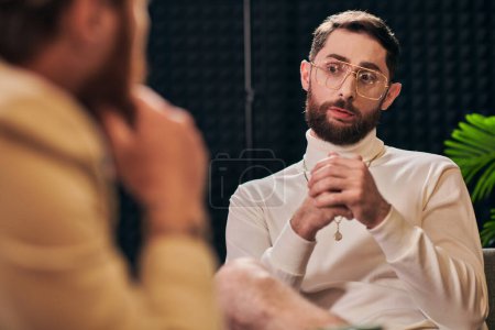 Photo for Handsome bearded man with glasses in elegant outfit sitting and looking at his interviewer - Royalty Free Image