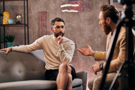hombres barbudos de buen aspecto en elegantes trajes elegantes sentado y discutiendo preguntas de la entrevista