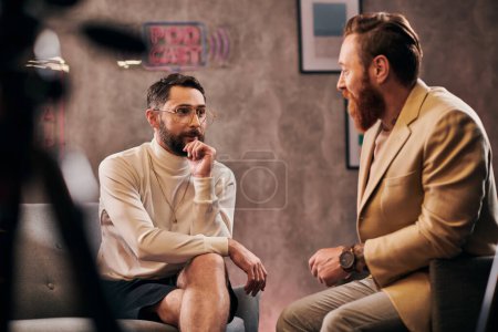 two attractive bearded men in elegant stylish attires sitting and discussing interview questions