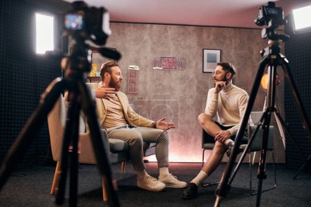 Foto de Guapos hombres elegantes con estilo elegante sentado y discutiendo preguntas de la entrevista en el estudio - Imagen libre de derechos