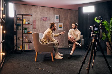 Foto de Hombres elegantes atractivos en ropa elegante sentado y discutiendo preguntas de la entrevista en el estudio - Imagen libre de derechos
