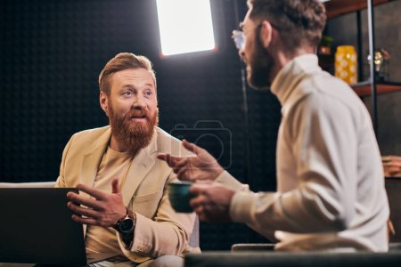 dos hombres guapos alegres en trajes elegantes con café y computadora portátil discutir preguntas de la entrevista