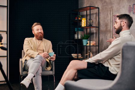 Foto de Alegres hombres guapos en ropa elegante con café discutir preguntas durante la entrevista - Imagen libre de derechos