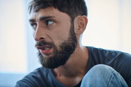 Kranker traumatisierter Mann mit Bart beißt sich während depressiver Episode die Lippen zu