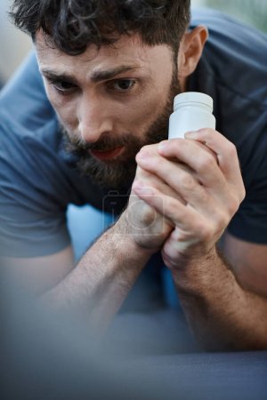 Foto de Hombre desesperado sosteniendo píldoras durante el episodio depresivo con autolesión, conciencia de salud mental - Imagen libre de derechos