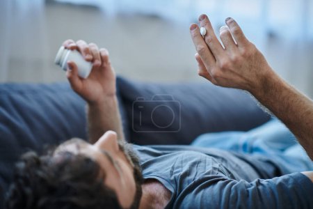 Kranker depressiver Mann mit Bart nimmt während depressiver Episode Tabletten, Bewusstsein für psychische Gesundheit