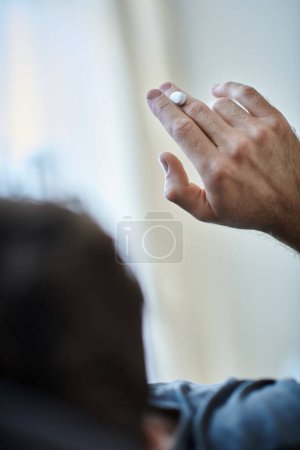 Foto de Vista posterior del hombre deprimido que toma pastillas durante el episodio depresivo, conciencia de salud mental - Imagen libre de derechos