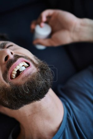 emotionaler depressiver Mann mit Bart, der während depressiver Episode Tabletten nimmt, Bewusstsein für psychische Gesundheit
