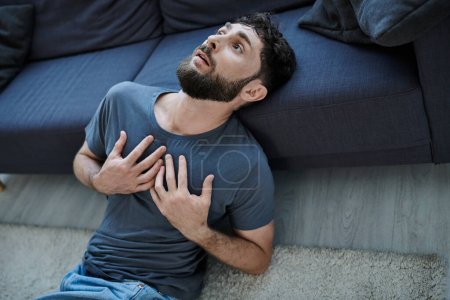 ill traumatized man with beard in home wear having severe panic attack, mental health awareness