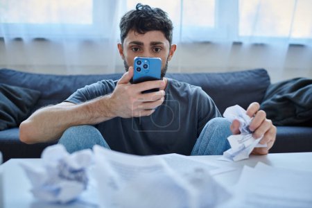 depressiv leidender Mann schaut während depressiver Episode auf sein Smartphone, psychische Gesundheit