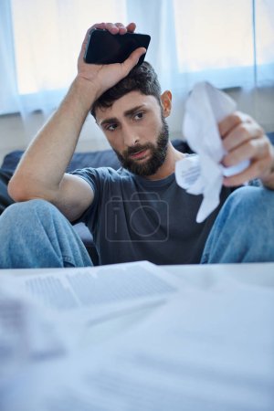 Photo for Bearded suffering man in casual attire looking at contract and pills during breakdown, mental health - Royalty Free Image
