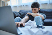 depressed man with beard in casual attire looking at his laptop during breakdown, mental health puzzle #694538786