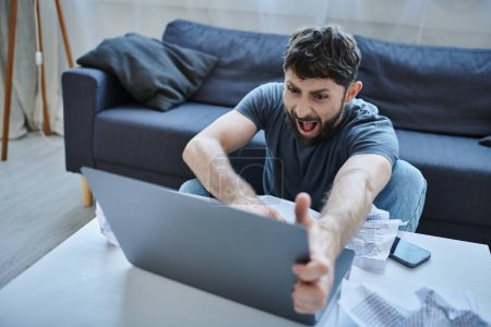 Foto de Hombre deprimido en traje casual gritando a su computadora portátil durante la crisis, conciencia de salud mental - Imagen libre de derechos