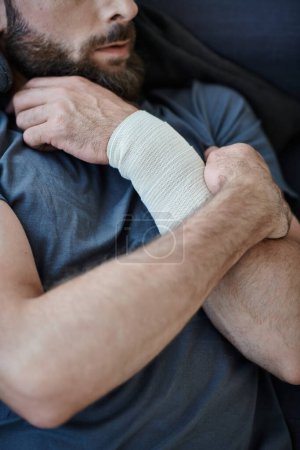 vista recortada del hombre deprimido con vendaje en el brazo después de intentar suicidarse, conciencia de salud mental