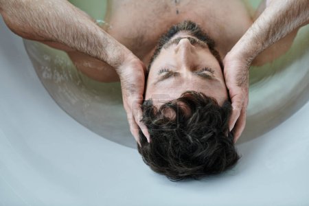 Foto de Hombre traumatizado deprimido con barba acostado en la bañera durante la ruptura, conciencia de salud mental - Imagen libre de derechos