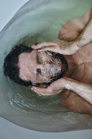 frustrated depressed man with beard drowning in bathtub during breakdown, mental health awareness