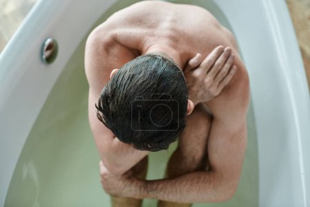 Téléchargez les photos : Anxieux homme déprimé avec barbe assis dans la baignoire pendant la dépression, conscience de la santé mentale - en image libre de droit