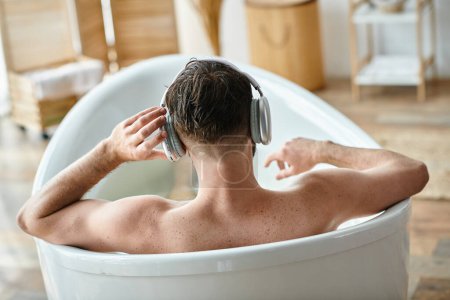 Rückenansicht des männlichen Modells, das aktiv in seiner Badewanne sitzt und sich entspannt, Bewusstsein für psychische Gesundheit