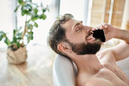 fröhlicher attraktiver Mann mit Bart, der in der Badewanne liegt und telefoniert, Bewusstsein für psychische Gesundheit