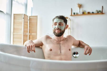 fröhlicher gutaussehender Mann mit Bart und Gesichtsmaske, der in seiner Badewanne chillt, Bewusstsein für psychische Gesundheit