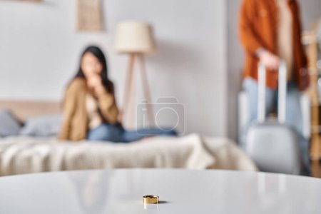 Selektiver Fokus des Eherings in der Nähe multiethnischer Paare, die sich im Schlafzimmer streiten, Scheidungskonzept