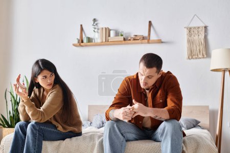 Téléchargez les photos : Couple multiethnique frustré assis et querelles dans la chambre à coucher à la maison, concept de divorce - en image libre de droit