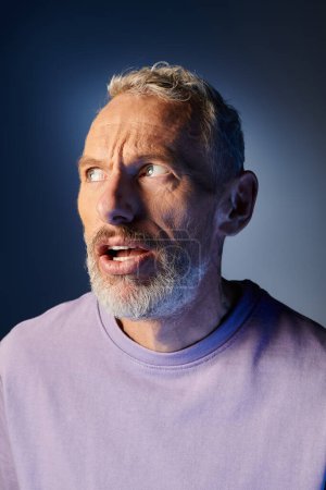 Photo for Handsome bearded mature man with accessories in stylish attire grimacing actively on blue backdrop - Royalty Free Image