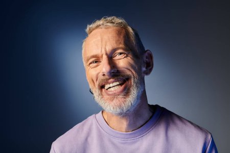 fröhlich attraktiver älterer Mann mit grauem Bart und lässiger trendiger Kleidung, der glücklich in die Kamera lächelt