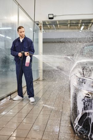 Téléchargez les photos : Attrayant professionnel travaillant dur dans un uniforme confortable avec les cheveux recueillis à l'aide de savon pour laver la voiture - en image libre de droit