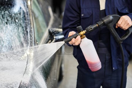 przycięty widok ciężko pracującego profesjonalnego żołnierza w niebieskim mundurze myjącego samochód z mydłem