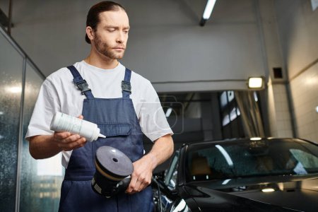 Photo for Good looking dedicated professional in comfy uniform applying paste on polishing machine in garage - Royalty Free Image