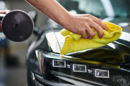 cropped view of hard working professional serviceman with polishing machine cleaning car with rag