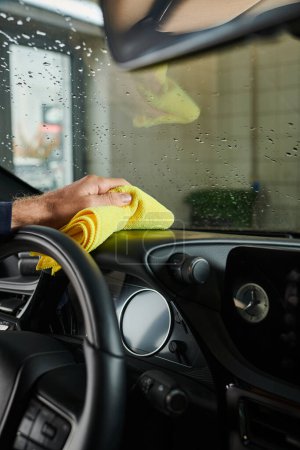 Photo for Cropped view of hard working professional serviceman cleaning glove compartment with yellow rag - Royalty Free Image