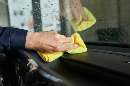 Photo for Cropped view of hard working professional in uniform using reg to clean glove compartment of car - Royalty Free Image