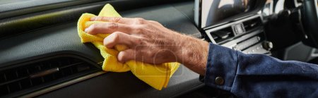 cropped view of hard working serviceman in uniform cleaning glove compartment of car with rag