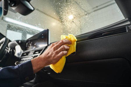 Photo for Cropped view of hard working professional in uniform cleaning glove compartment with yellow rag - Royalty Free Image