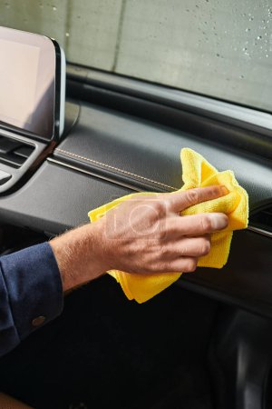 Photo for Cropped view of devoted hard working serviceman in uniform cleaning glove compartment with rag - Royalty Free Image