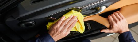 Photo for Cropped view of hard working specialist in comfortable uniform cleaning car door with rag, banner - Royalty Free Image