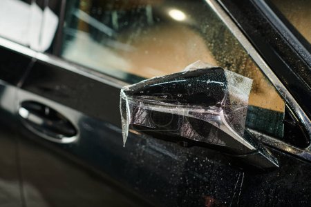 Foto de Objeto de la foto de la película protectora aplicada cuidadosamente en el espejo de la vista lateral del coche moderno negro - Imagen libre de derechos