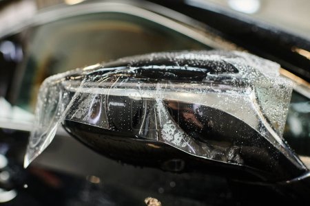 Foto de Foto del objeto de lámina protectora transparente aplicada en el espejo de la vista lateral del coche moderno negro - Imagen libre de derechos