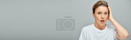 Photo for Appealing surprised blonde woman with collected hair and contact lenses looking at camera, banner - Royalty Free Image