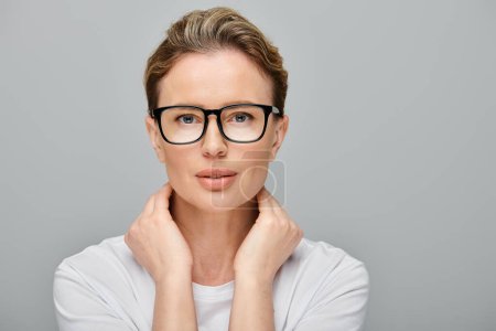 appealing blonde female model with blonde hair and glasses looking at camera on gray backdrop