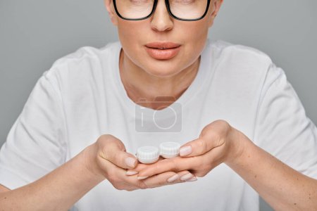 Ausgeschnittene Ansicht einer Frau in Freizeitkleidung mit Brille und Kontaktlinsen in der Hand